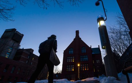 a student walks through campus lit by a security kiosk